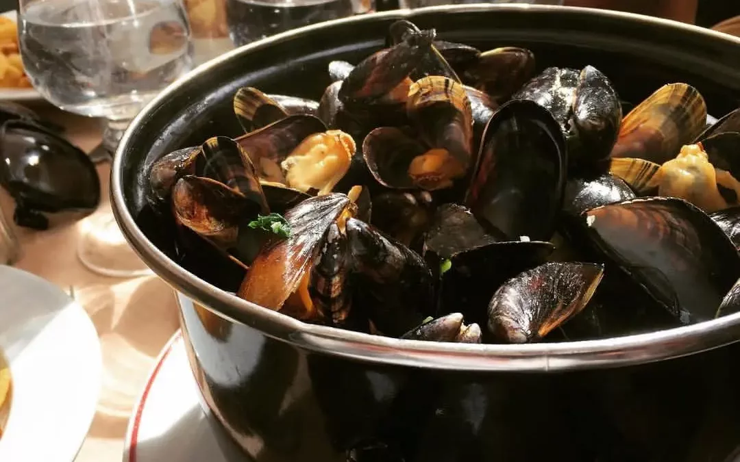 Pot of fresh moules-frites served on a sunny terrace table during the Braderie de Lille