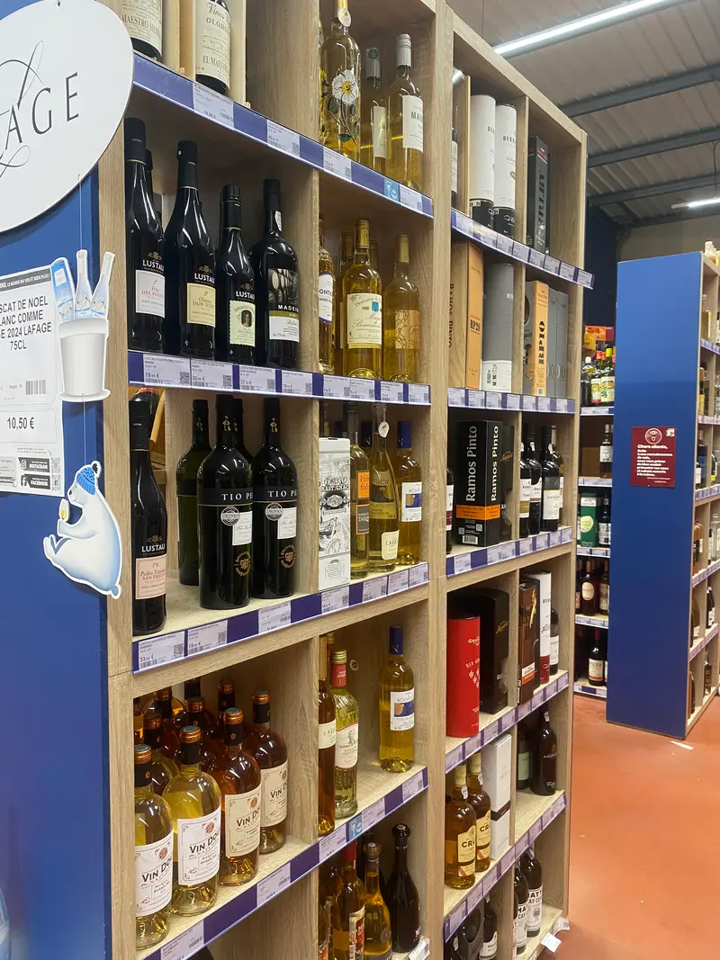 Selection of fortified wines, sherry and dessert wines displayed on wooden shelves at Calais Vins.