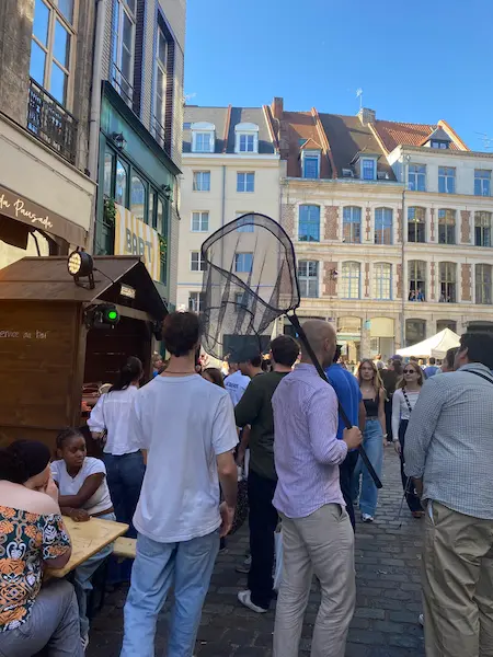 Man carrying a large fishing net through the crowds at the Lille Braderie