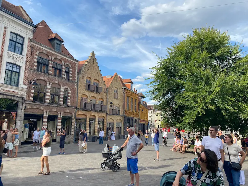 Historic brick and stone houses with stepped gables overlooking a lively square in Old Lille, Northern France.